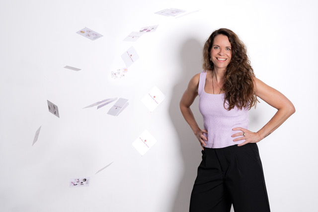 Sylvia lachend voor een muur met rondvliegende State Shift kaarten