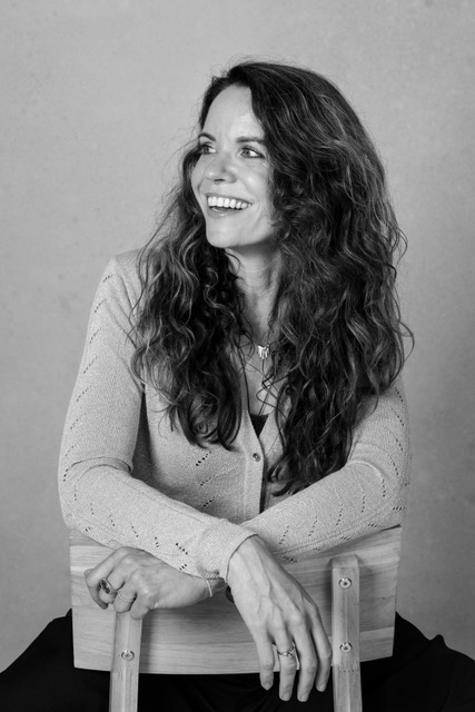 Sylvia Holtslag lachend op een stoel, zwart-witfoto